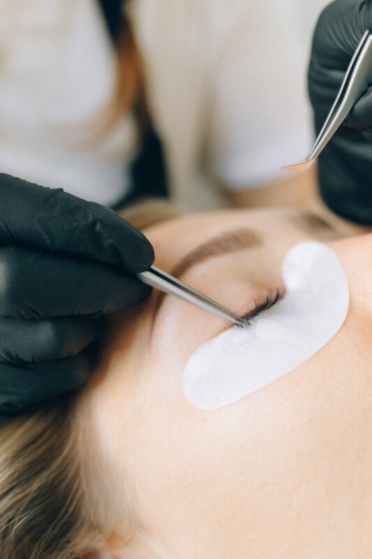 Hands Putting Cosmetic Eyelashes on Client's Eye